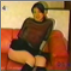 An attractive Asian girl farts while sitting on a sofa.